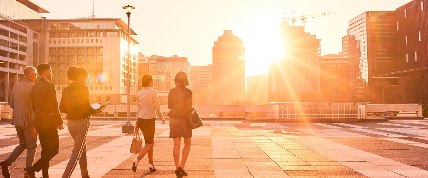 a group of people walking on a brick walkway with a fountain in the background